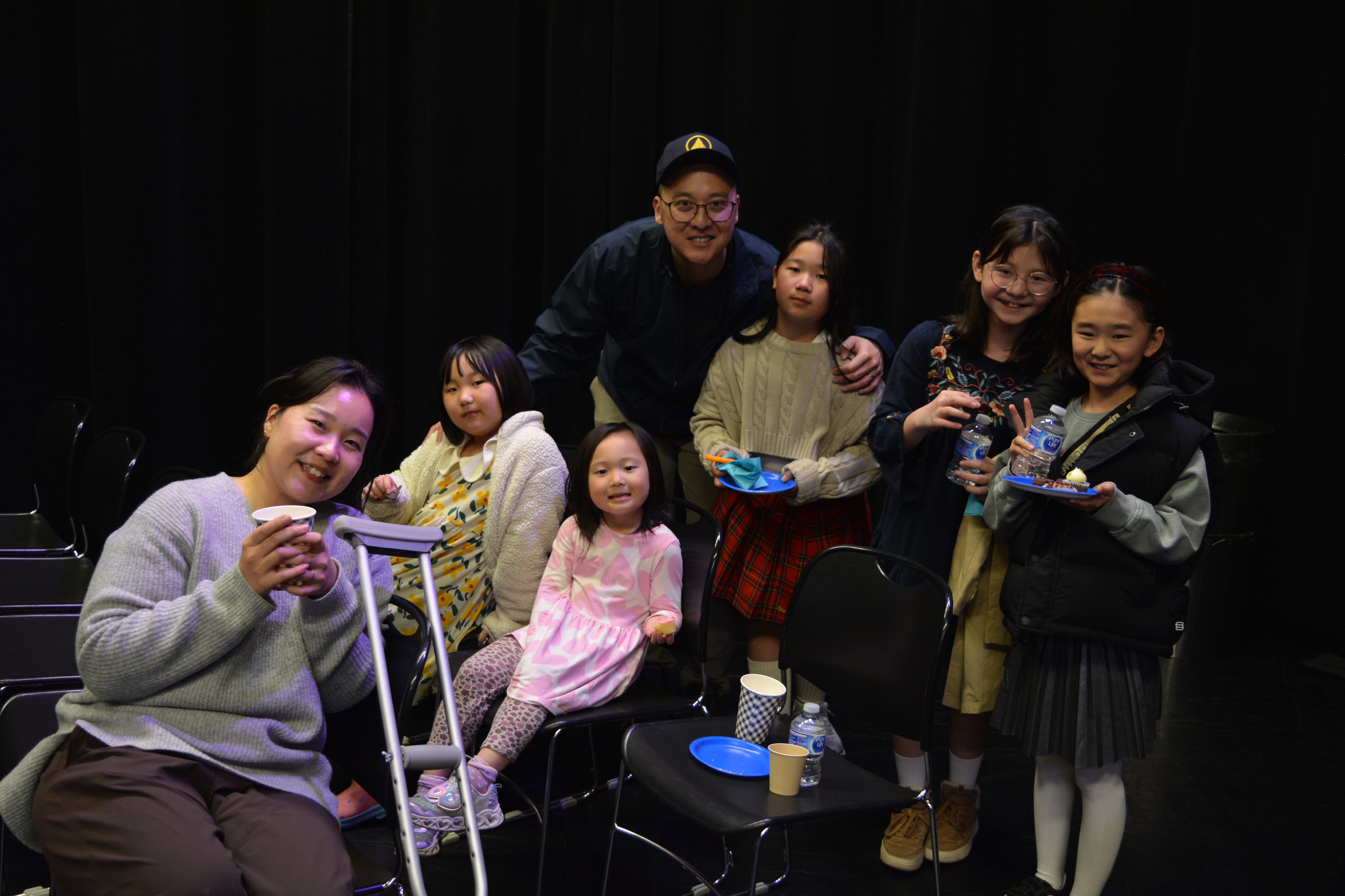 A large, supportive family hugging their child after a successful music performance, serving families from Surrey and Burnaby.