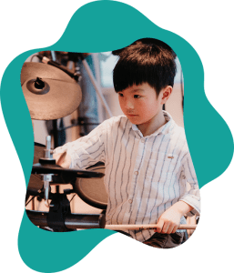 A young drummer practicing beats and styles like jazz and pop in our music school serving Coquitlam.